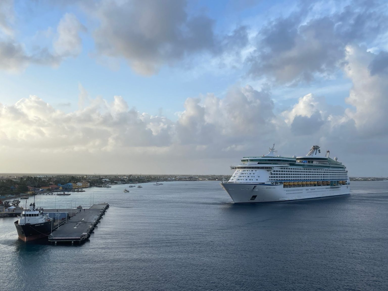 Navio de cruzeiro se aproxima de um píer em um dia nublado.