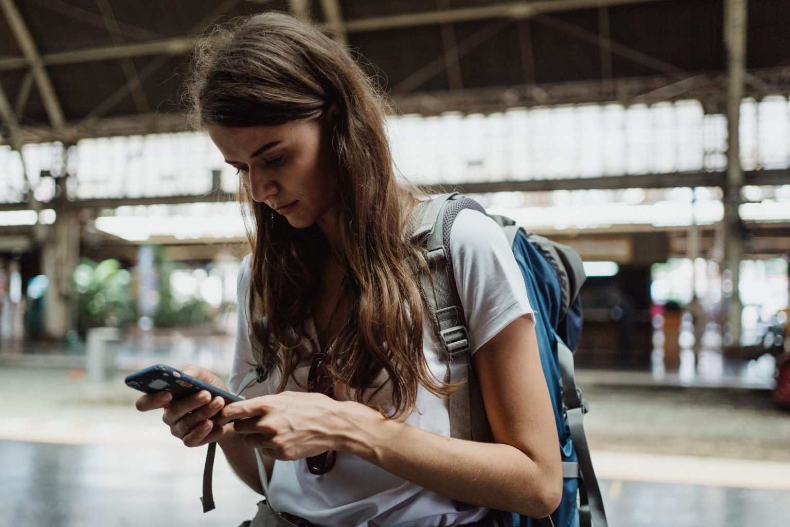 Mulher viajante consulta o celular em uma estação de trem.