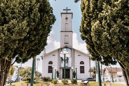 Igreja católica cercada por árvores, em um dia ensolarado, no estado de Goiás.