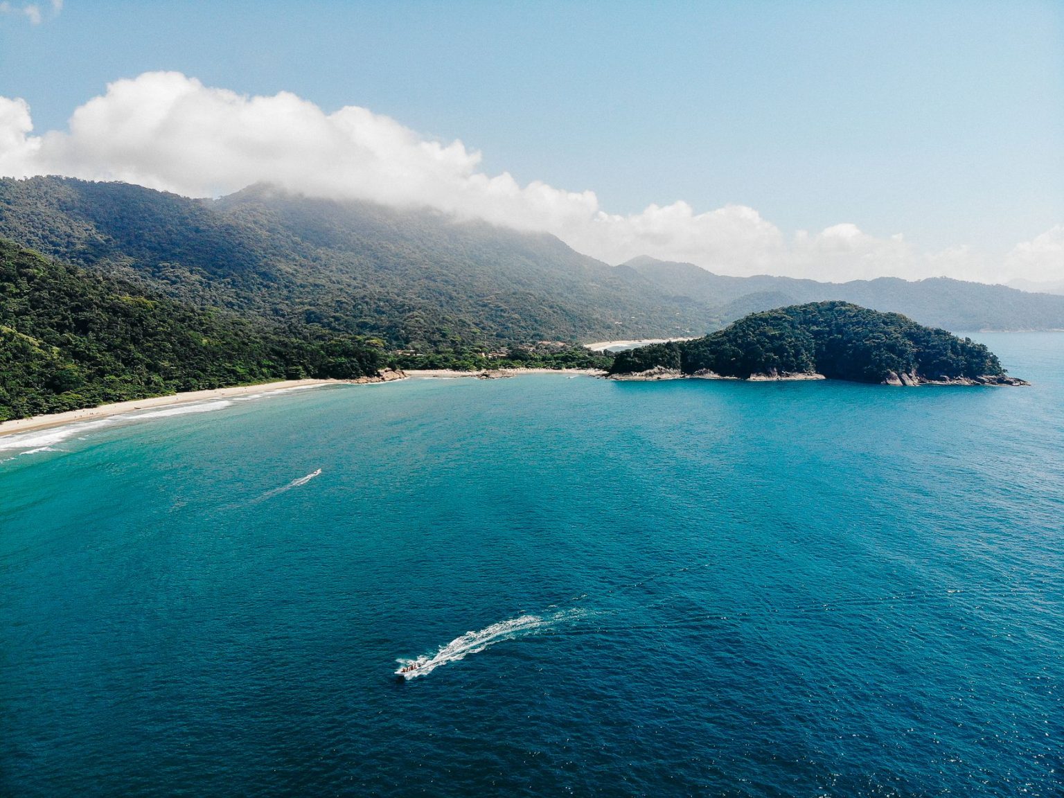 Vista aérea da costa verdejante da Ilha Grande, com águas azul-turquesa e trechos de Mata Atlântica.