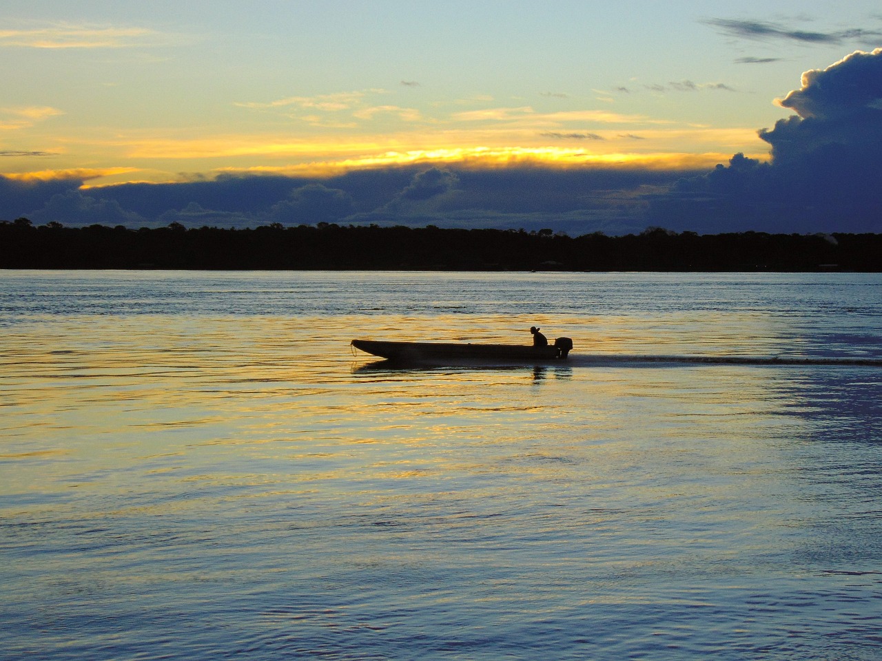Rio de Porto Velho ao entardecer, com uma embarcação sobre a água e o horizonte ao fundo